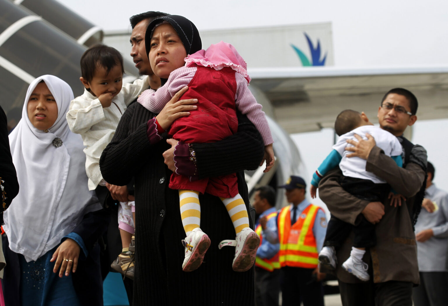 A group of Indonesian migrant workers and their families at an airport, waiting to board a plane to go overseas for work.